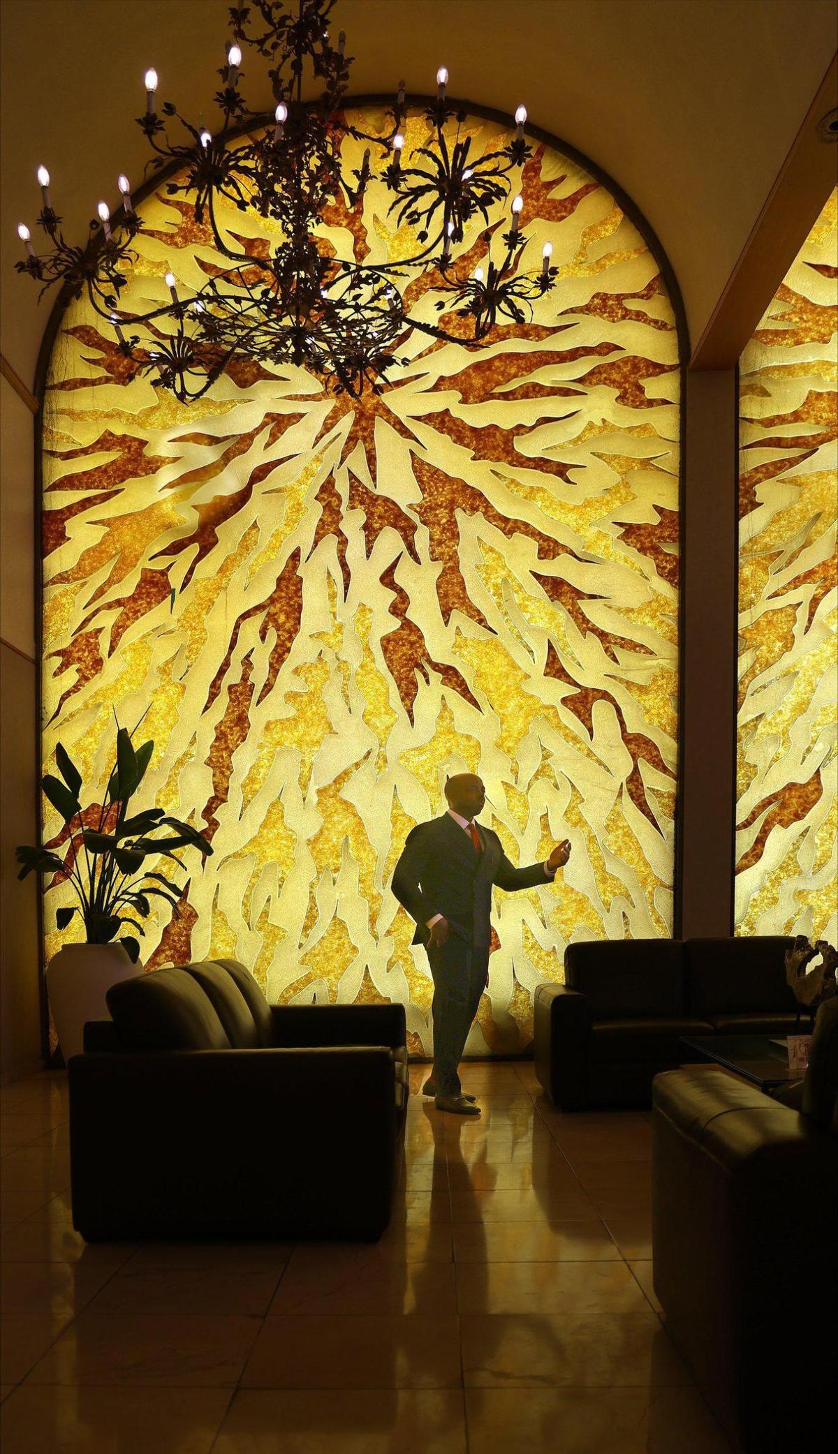 St. Fort’s Funeral Home owner and funeral director Evans St. Fort stands next to one of the 20-feet-tall stained glass windows at his North Miami Beach facility on Thursday, May 29, 2025.