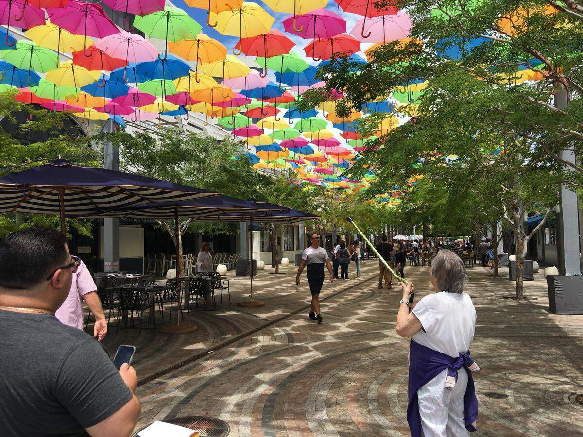 Pedestrians take pictures and point in admiration at the Umbrella Sky art installation above the Giralda Plaza promenade during the summer of 2018. Coral Gables is searching for another artist to try and recapture the magic of that public art installation.