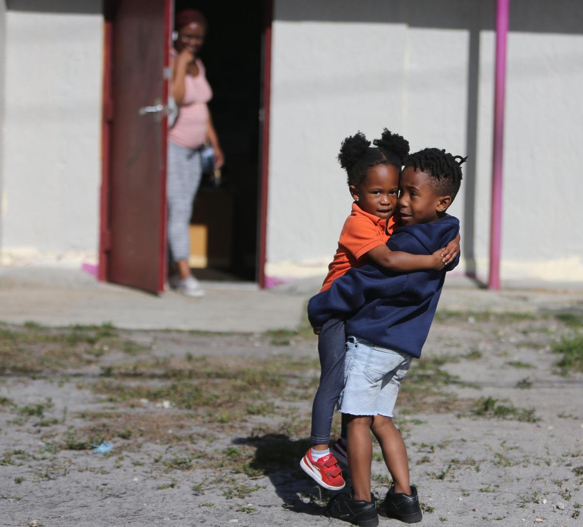 Zuri Taylor, 3, is lifted up in a welcoming greeting by her big brother, Keiraun Stewart, 5, as their mom, Zakyra Taylor, waits in the doorway to take them home at the end of their day at Excel Kids Academy in Miami Gardens. The Miami Gardens preschool and aftercare center is open and operating under new guidelines due to COVID-19 precautions.