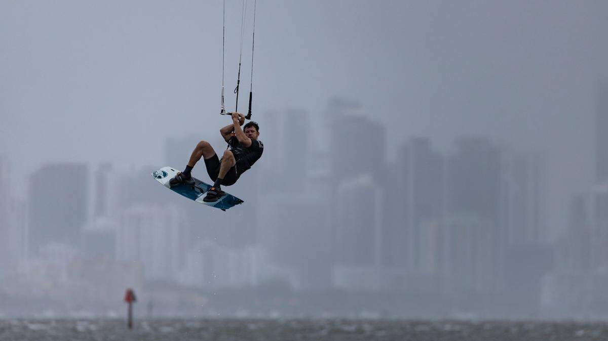 A kite boarder catches waves as rain makes its way over Brickell as seen from Matheson Hammock Park on Tuesday, April 11, 2023, in Coral Gables, Fla.