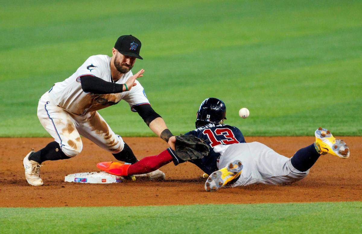 Miami Marlins shortstop Jon Berti (5) is unable to fields throw as Atlanta Braves right fielder Ronald Acuna Jr. (13) steals second during the second inning of a baseball game at loanDepot park on Thursday, May 4, 2023 in Miami, Florida.