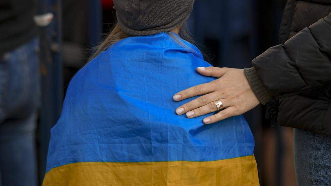 A woman puts her hand on the back of a child draped in the Ukrainian flag during a protest against Russia’s war in Ukraine, in front of the Russian embassy in Bucharest, Romania in March.