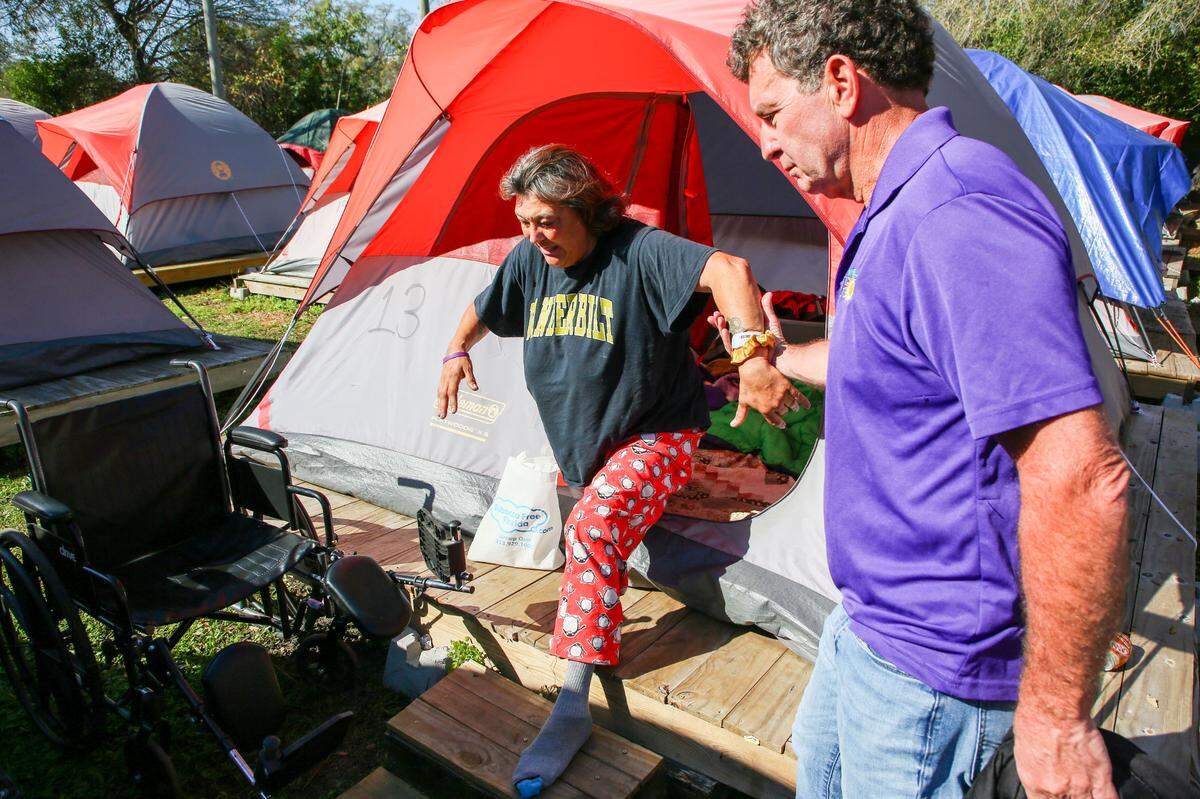Pinellas Hope tent community resident Angela Martin, center, is helped to her wheelchair by program director Joe Pondolfino on Tuesday, Feb 27, 2024, in Clearwater.