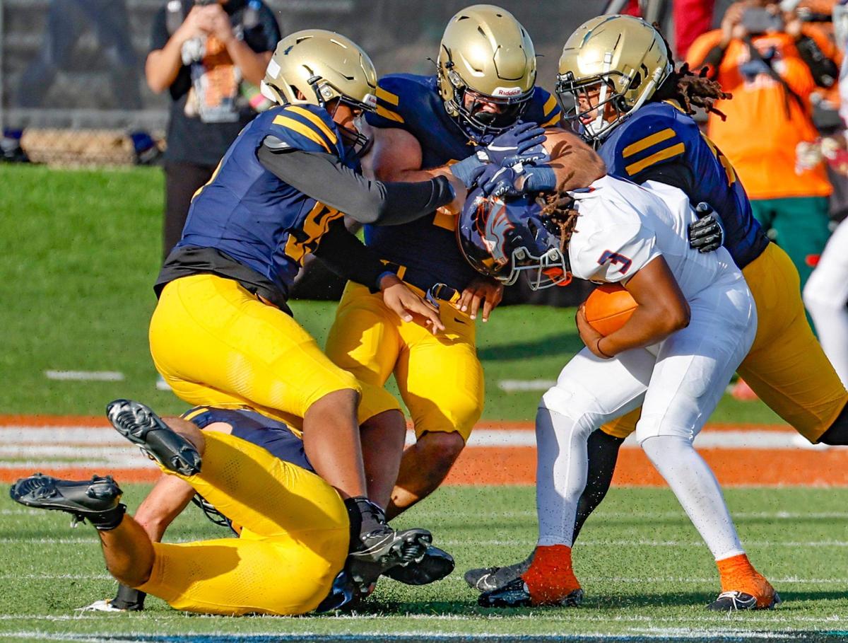 Homestead Broncos quarterback Joshua Townsend (3) is taken down by St. Thomas Aquinas defenders in the first half during the Class 3M state championship at Bragg Memorial Stadium in Tallahassee, Florida, on Saturday, December 9, 2023.