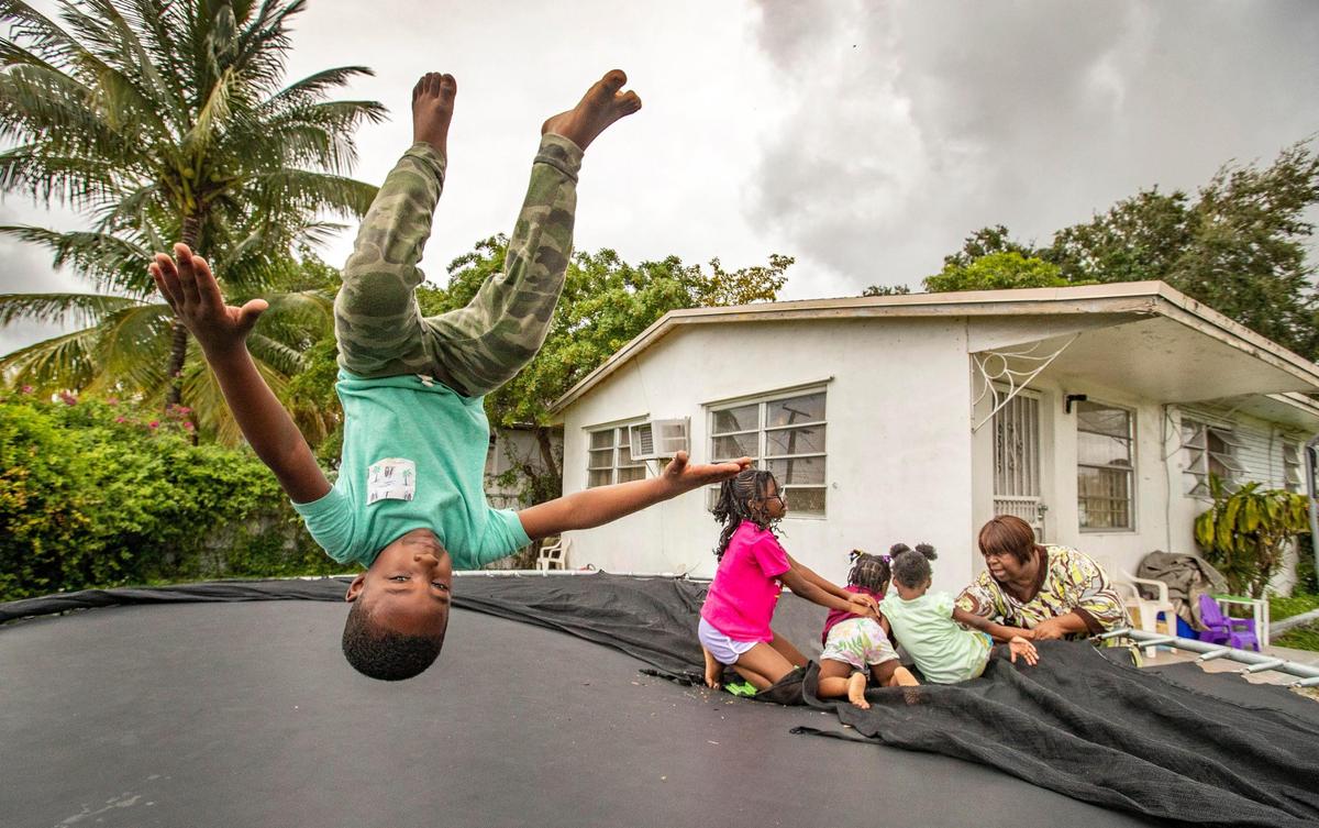 Loyal, 6, jumps on a trampoline as his grandmother, Joan Pratt, 62, talks with his sisters, Oliviea, 10, Abigail, 3, and Terylin, 5, in the yard of their Liberty City home in Miami on Nov. 7, 2020.