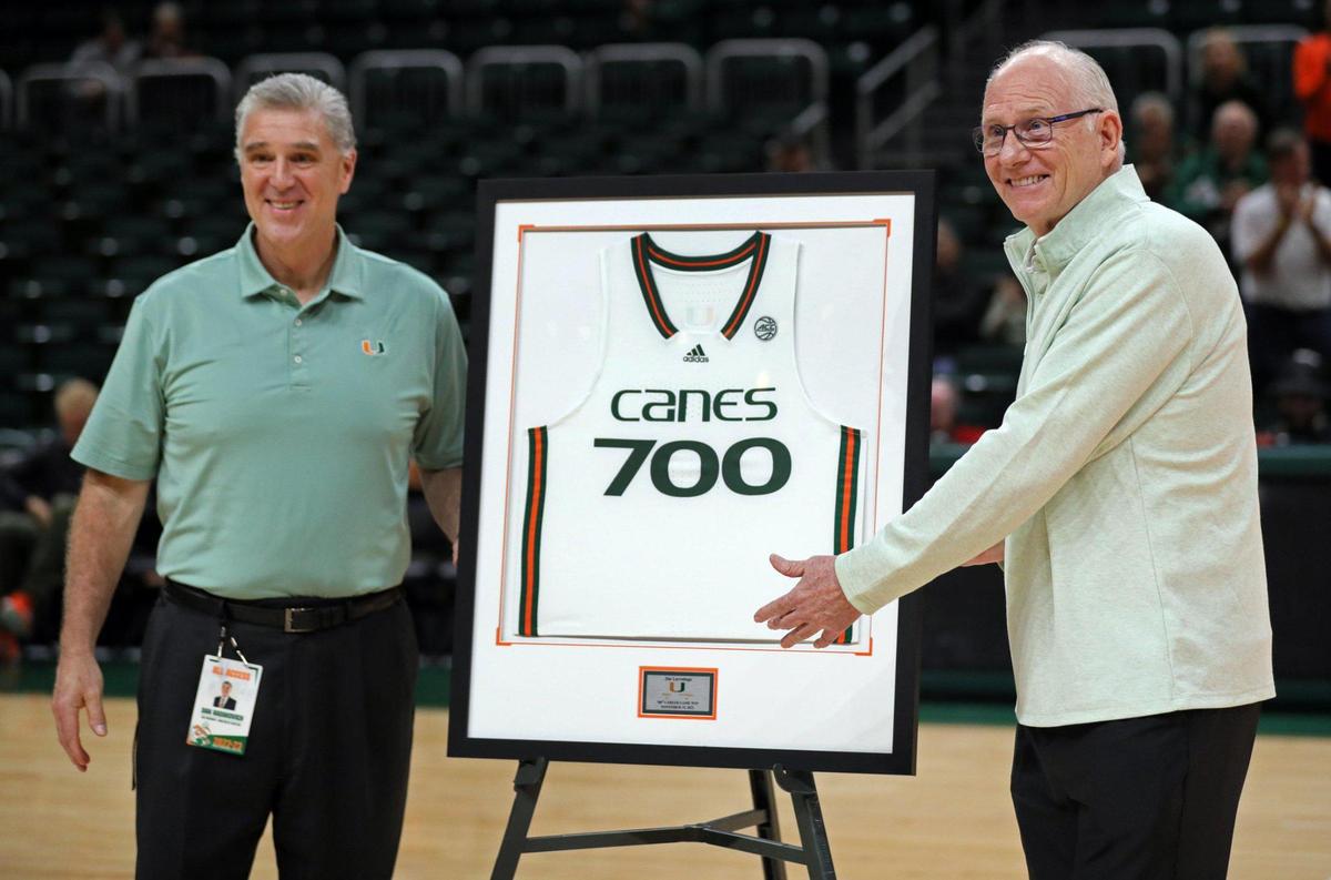 Miami Hurricanes Athletic Director Dan Radakovich, at left, joins men’s basketball coach Jim Larrañaga, at right, who is honored after winning 700 games during his career before the game against the Rutgers Scarlet Knights at the Watsco Center in Coral Gables on Wednesday, November 30, 2022.