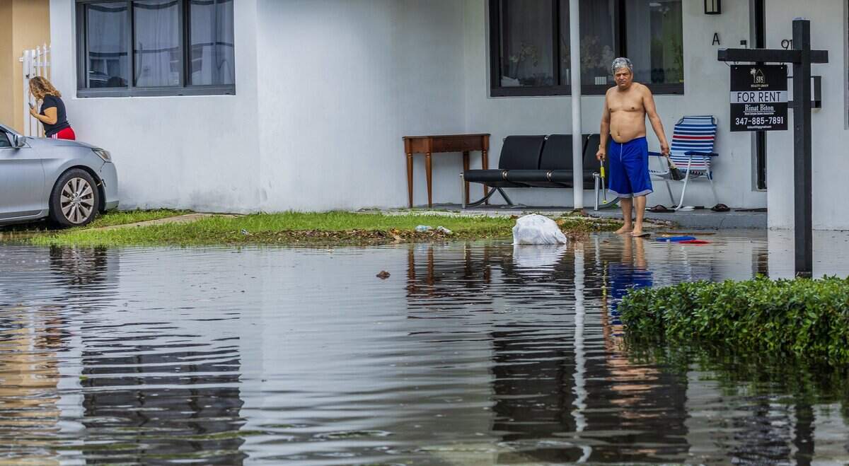 Andres Bonilla and his wife Maria Martel watch as the floodwaters cover the front yard of their home on 79th Terrace and Crespi Boulevard in Miami Beach.