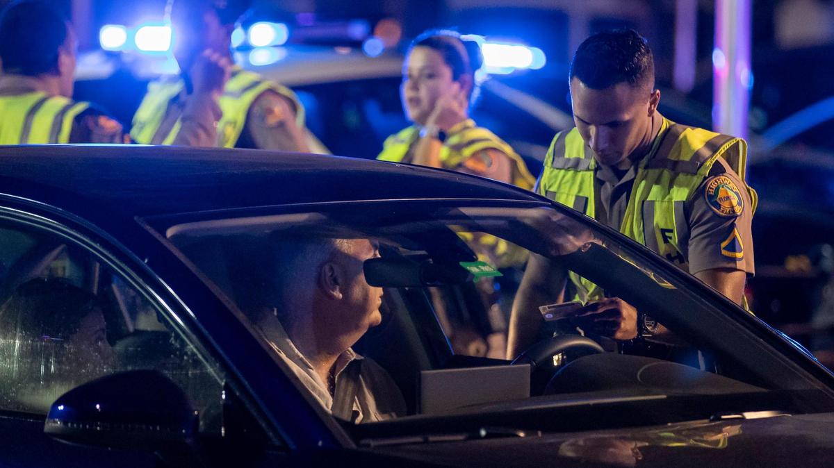 A Florida Highway Patrol officer talks with a driver at a checkpoint along 5th Street on Friday, March 24, 2023 in Miami Beach, Fla. After two deadly shootings, city officials voted not to re-impose a midnight curfew, but implemented an emergency order banning alcohol sales after 6 p.m.