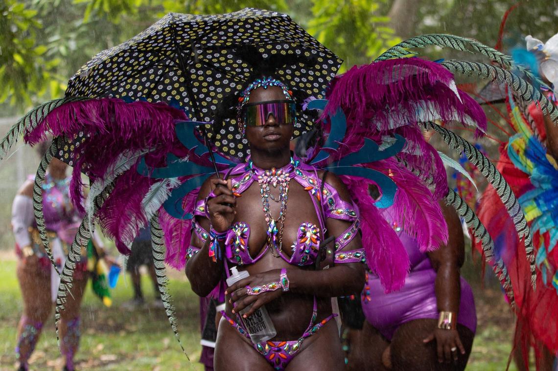 A performer holds an umbrella while waiting for rain to pass during Miami Carnival at the Miami-Dade County Fair Expo in Miami, Florida on Sunday, October 9, 2022.