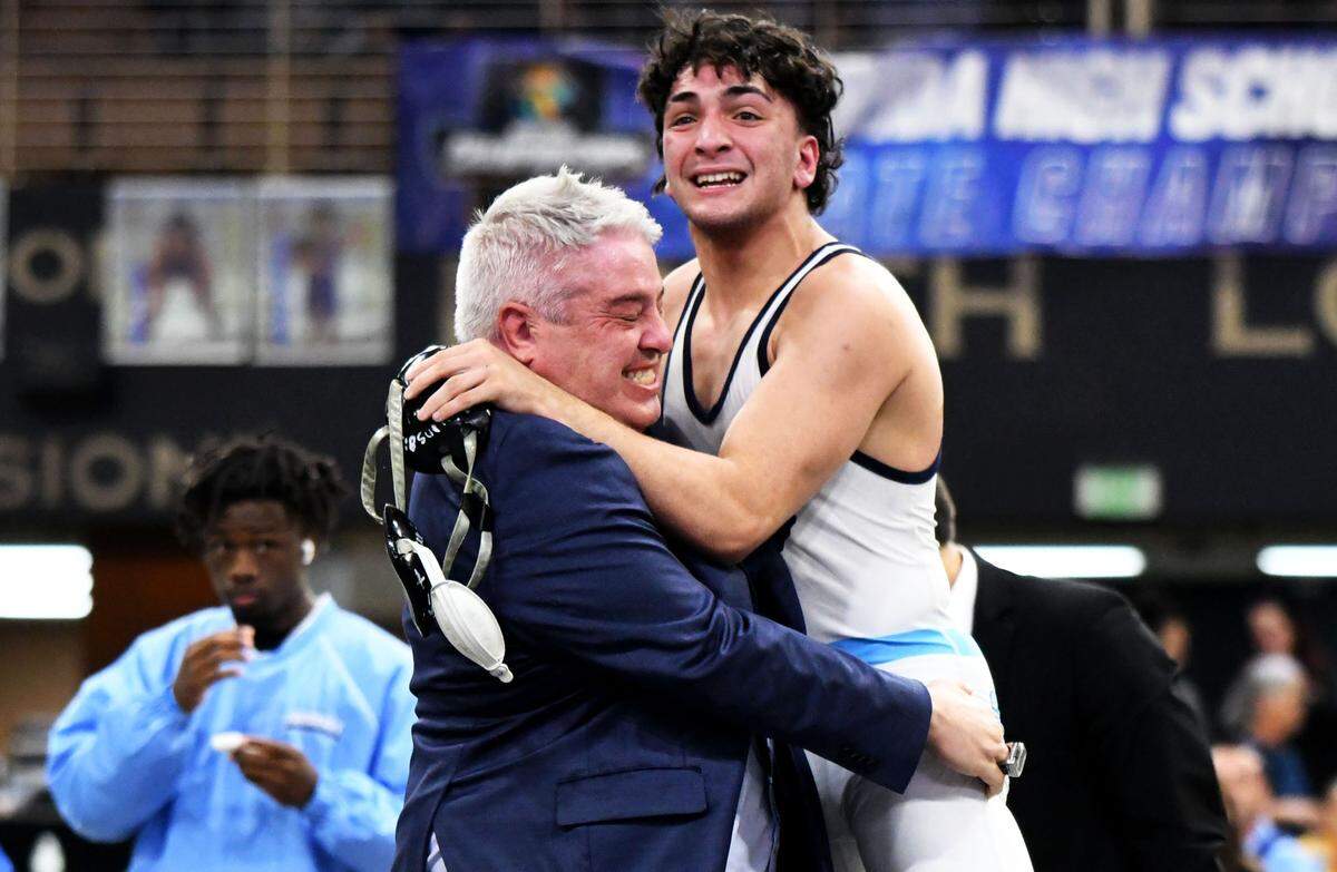 Somerset Academy junior Tristian Sainz hugs head coach Joe Blasucci after winning the Class 2A 150-pound championship in dramatic fashion on Saturday at the FHSAA IBT wrestling state championships at Silver Spurs Arena in Kissimmee.