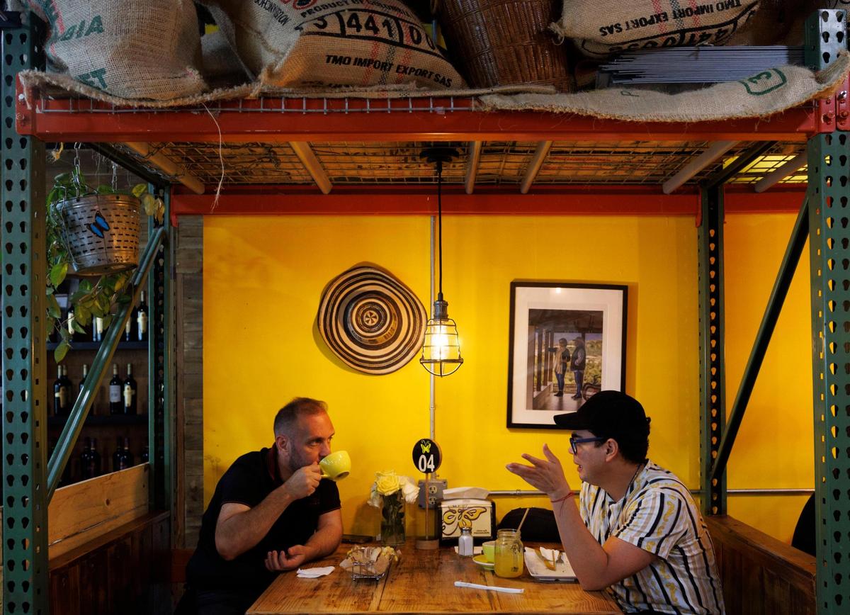 Osman Aray, right, and another customer enjoy coffee and food at Macondo Coffee during the morning on Tuesday, Feb. 18, 2025, in Doral, Florida.