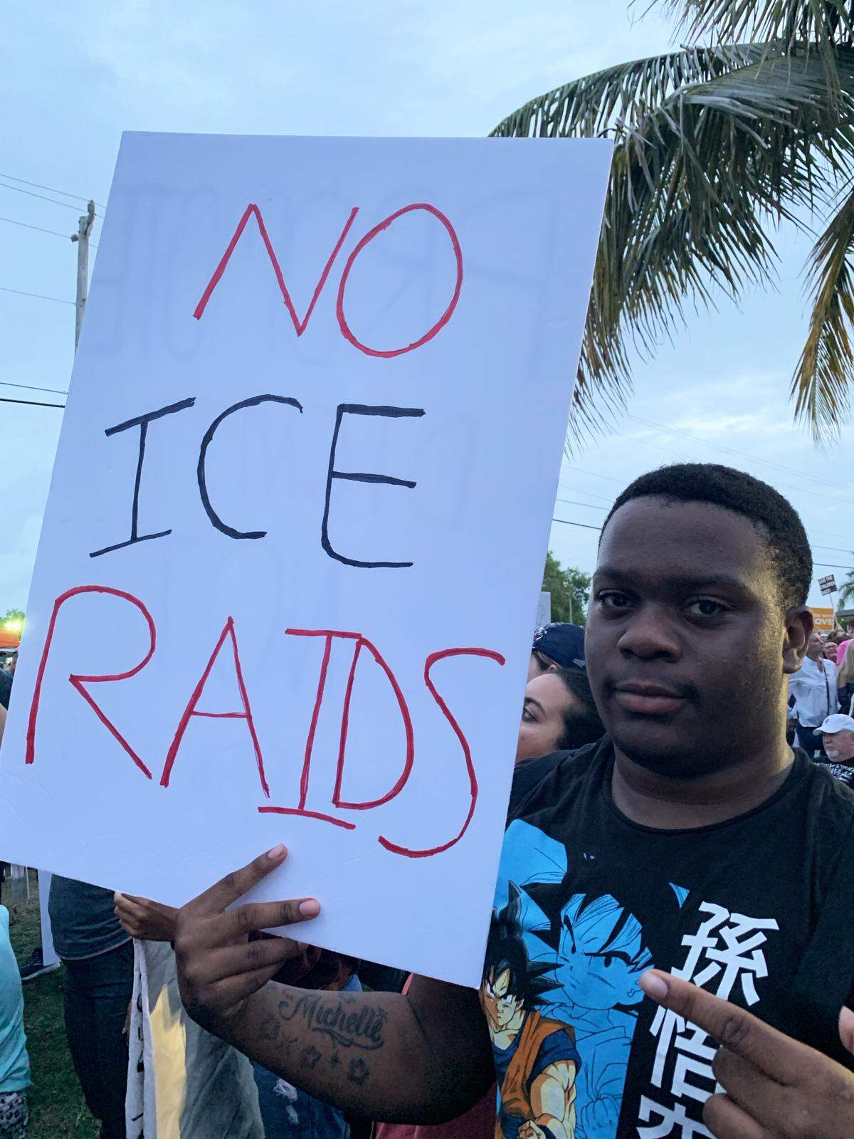 Tray Young, a 15-year-old student at Homestead High School, holds a sign denouncing federal immigration raids expected on Sunday during a protest outside the Homestead migrant shelter Friday night.