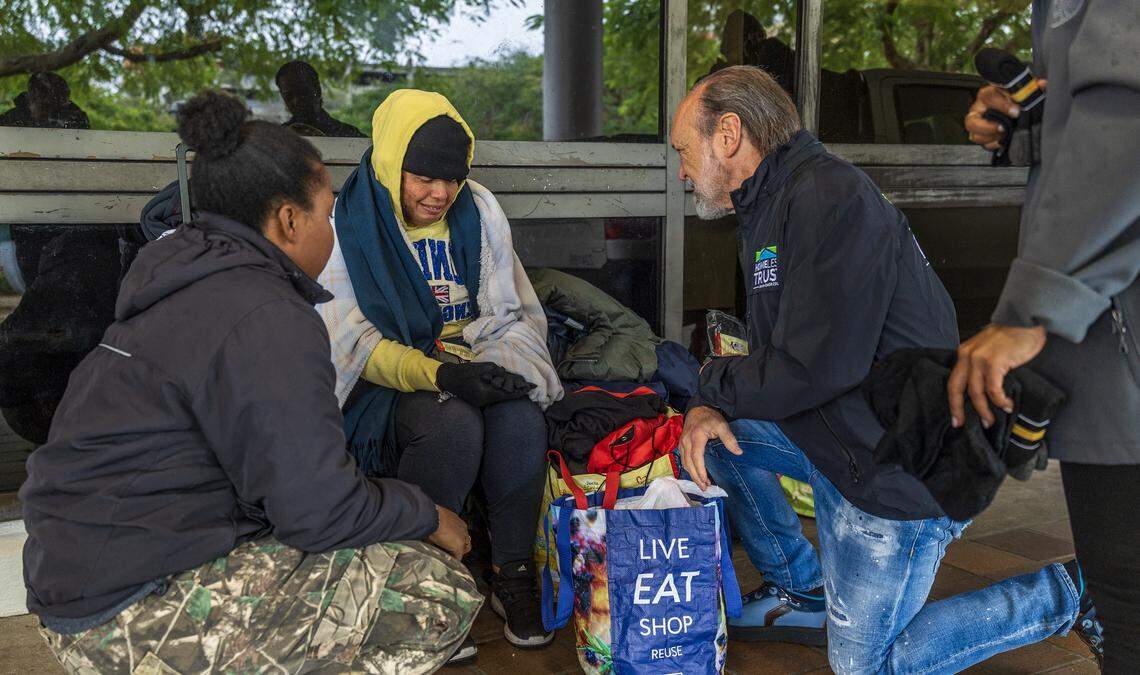 Shaunie Chambers, left, and Miami-Dade County Homeless Trust Chairman Ronald L. Book hand out cold-weather items to a homeless woman on Saturday, Jan. 31, 2026, near the Stephen P. Clark Center in downtown Miami. 
