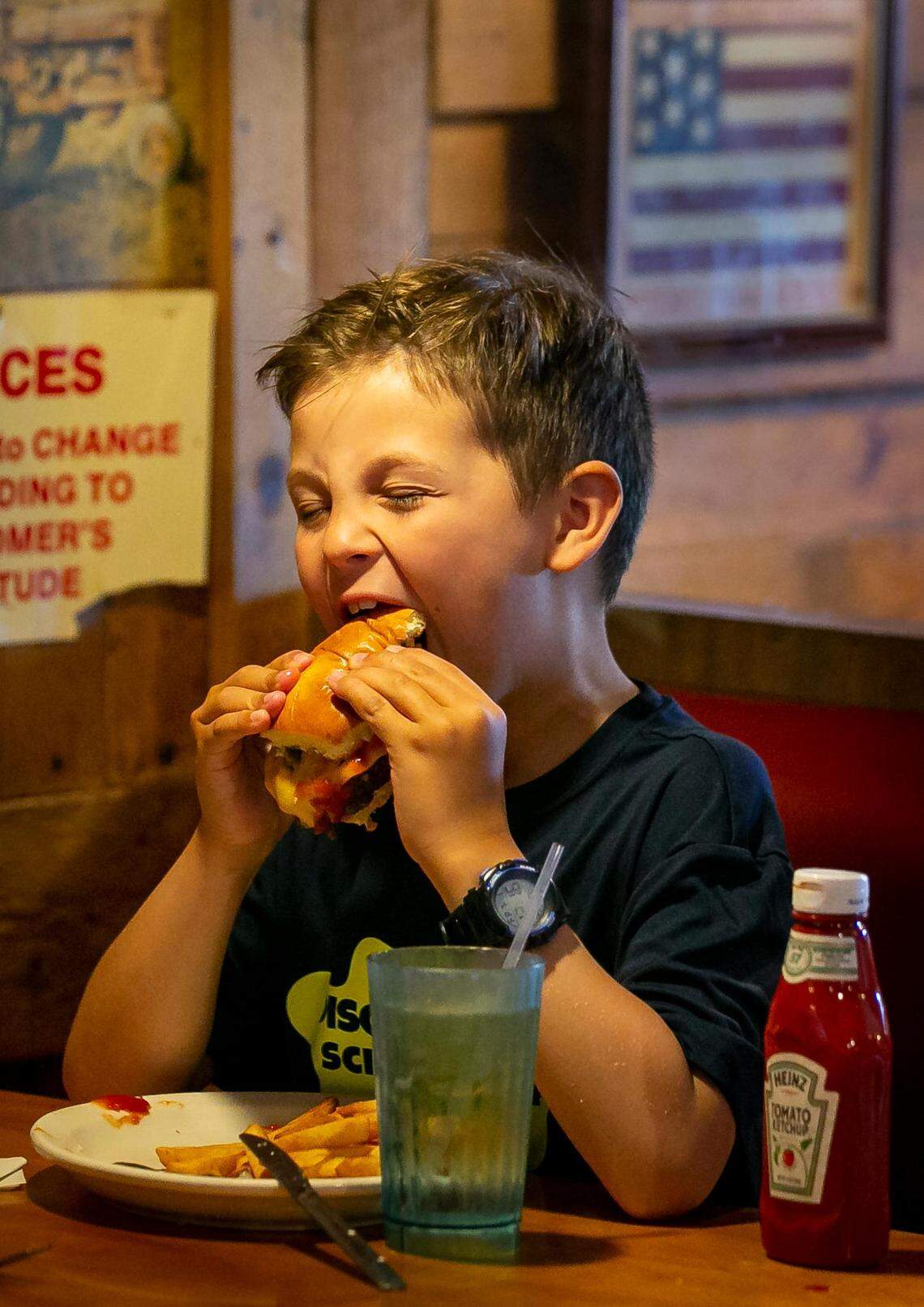 Luca Vidal, 7, takes a bite of the cheeseburger he ordered at Wagons West Restaurant on July 1, 2022,  in Pinecrest.