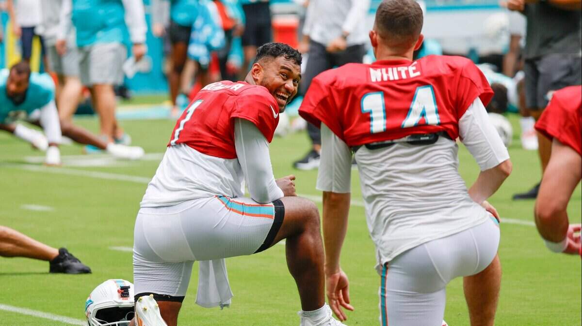 Miami Dolphins quarterback Tua Tagovailoa (1) reacts as he interacts with quarterback Mike White (14) during stretches during a team scrimmage at Hard Rock Stadium in Miami Gardens on Saturday, August 5, 2023.