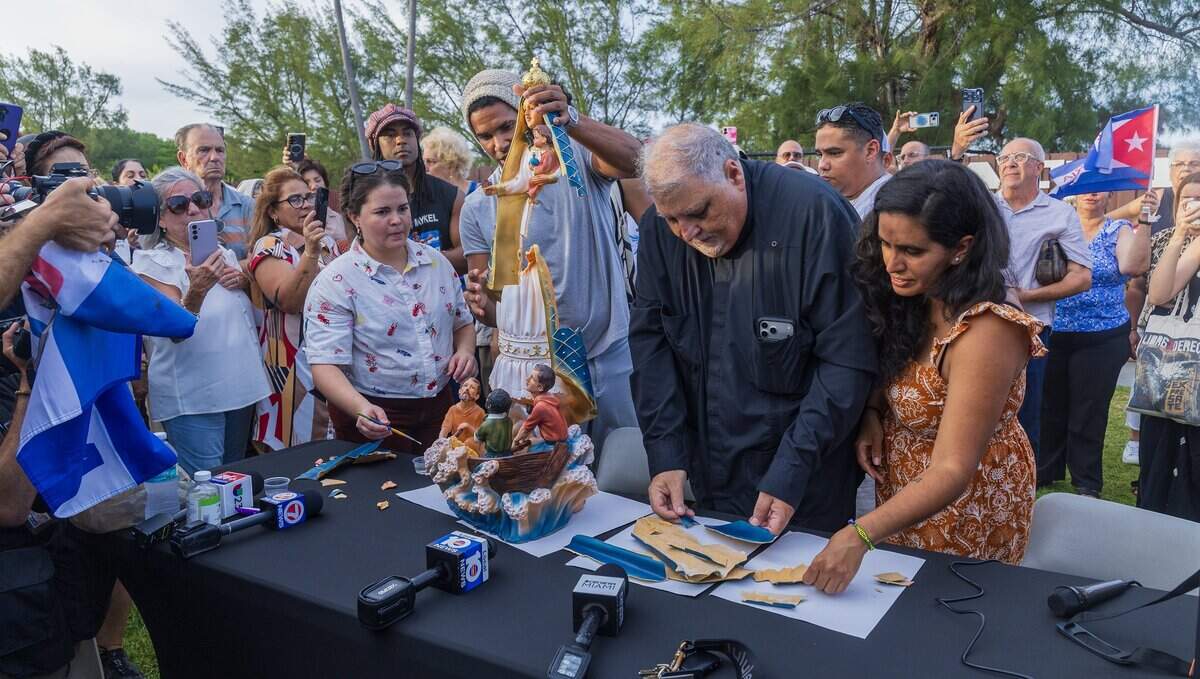 El reverendo José Joaquin Espino se unió a Salomé García (extrema izquierda) y a Anamely Ramos (extrema derecha) para ayudar al artista disidente cubano Luis Manuel Otero Alcántara a recomponer una imagen de la Virgen María que trajo desde Cuba a Our Lady of Charity National Shrine el sábado.