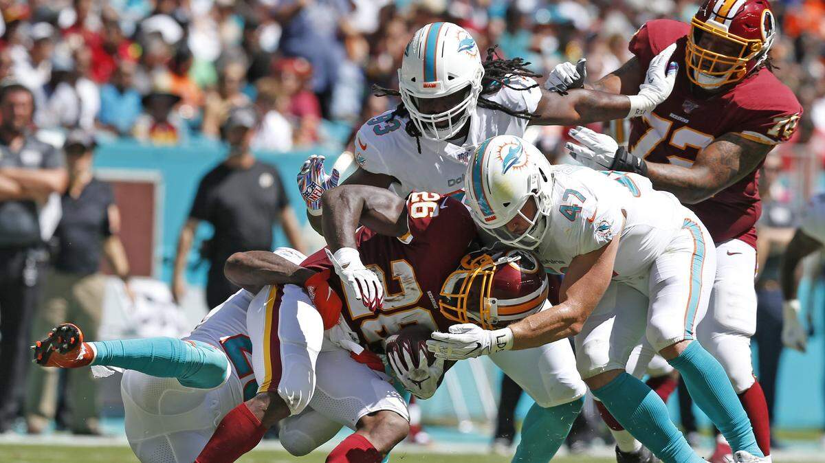 Miami Dolphins defensive end Avery Moss (93), linebacker Vince Biegel (47) and free safety Reshad Jones (20) gang tackle Washington Redskins running back Adrian Peterson (26) in the first quarter as the Miami Dolphins host the Washington Redskins at Hard Rock Stadium in Miami Gardens on Sunday, October 13, 2019.