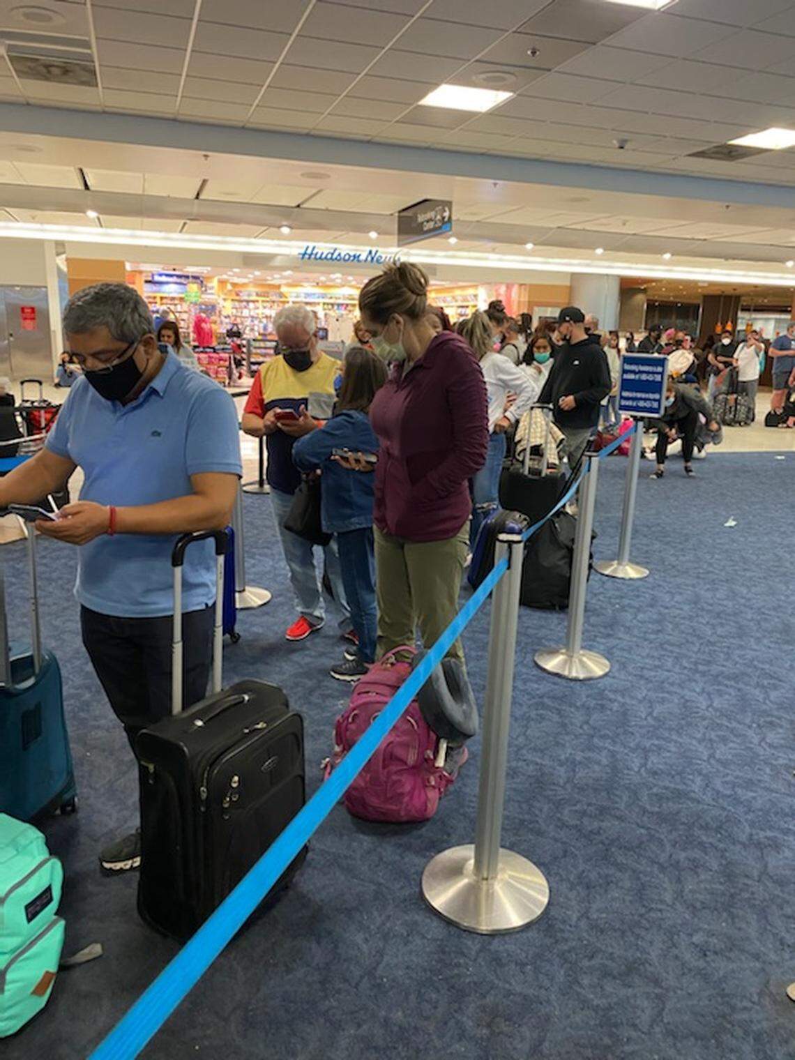 People stand in a rebooking line at the American Airlines terminal in Miami International Airport Friday, April 1, 2022. Airport officials say stormy weather Thursday and Friday caused flight cancellations and backups.