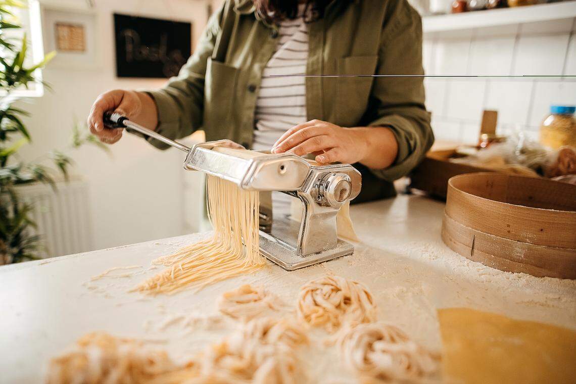 Photo of a young woman making homemade pasta in the kitchen of her apartment