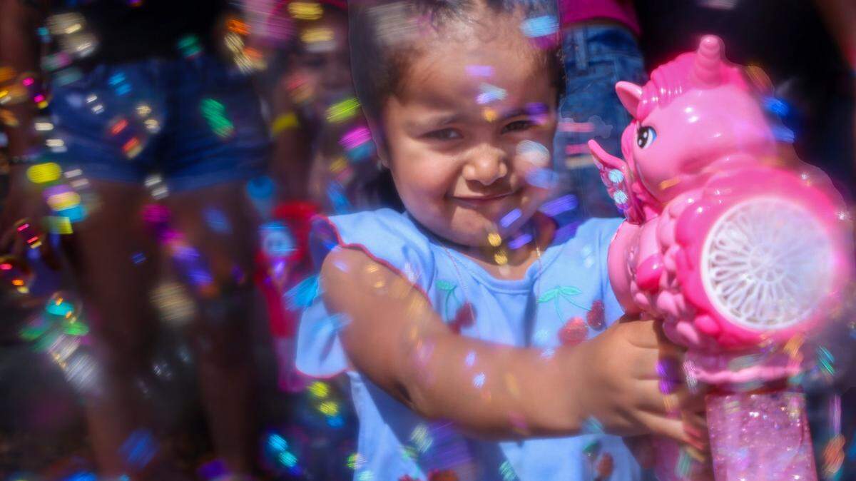 Destiny Arancivia, 3, showers friends and relatives with bubbles from her pink “My Little Pony” bubble machine.