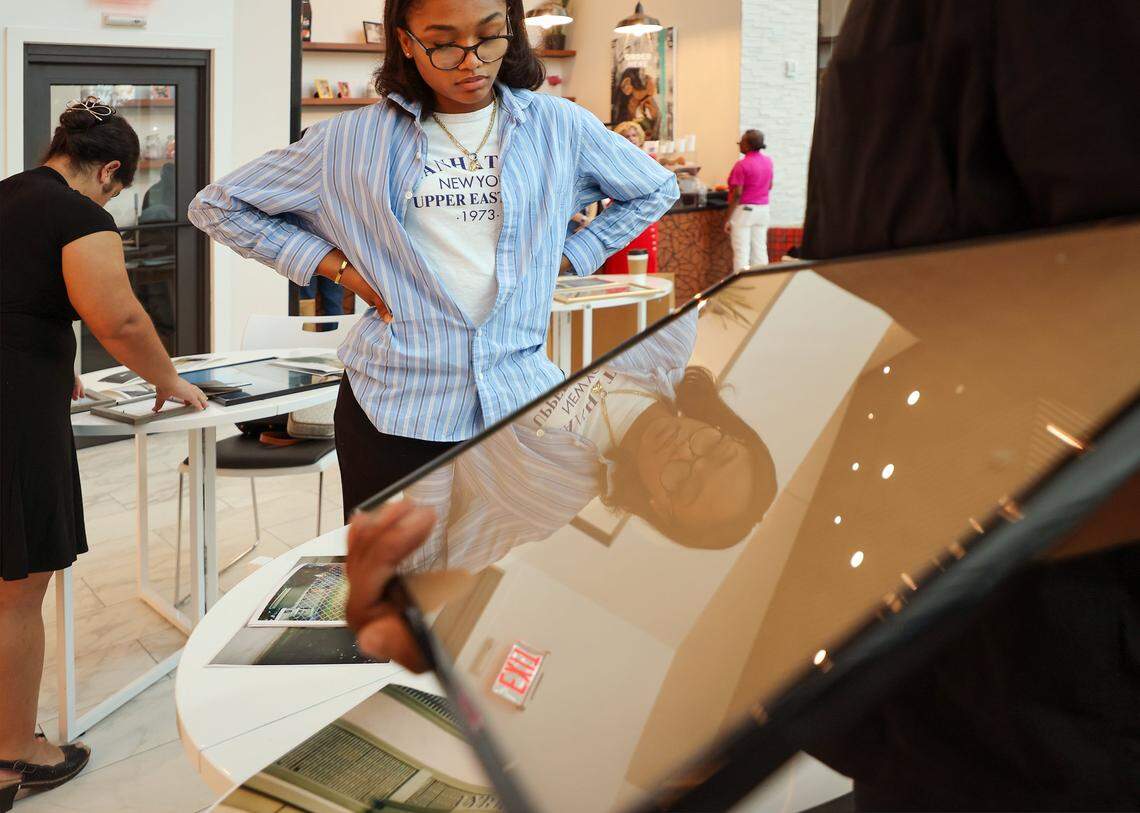 Miami Art Charter student Cade Hardy, 16, center, gets assistance from Nyya Toussaint, right, while Hannah Cabrera, 17, left, and others start framing photos in preparation for the upcoming art exhibition. Four high school students installed photos inside the First Church Miami coffee shop for the exhibition Sparrow, featuring the photography of local photographers navigating homelessness under the artistic direction of Miami-based artist Christopher Mitchell on Sunday, November 30, 2025.