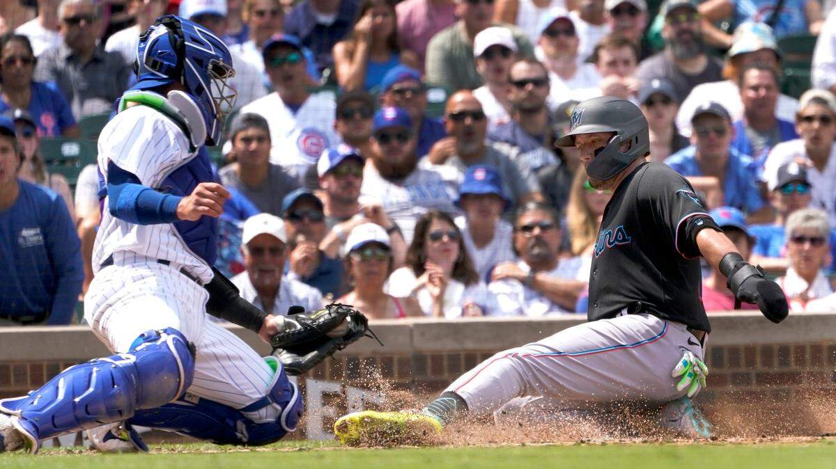 Chicago Cubs catcher P.J. Higgins, left, tags out Miami Marlins’ Miguel Rojas at home during the third inning of a baseball game Saturday, Aug. 6, 2022, in Chicago. (AP Photo/Charles Rex Arbogast)