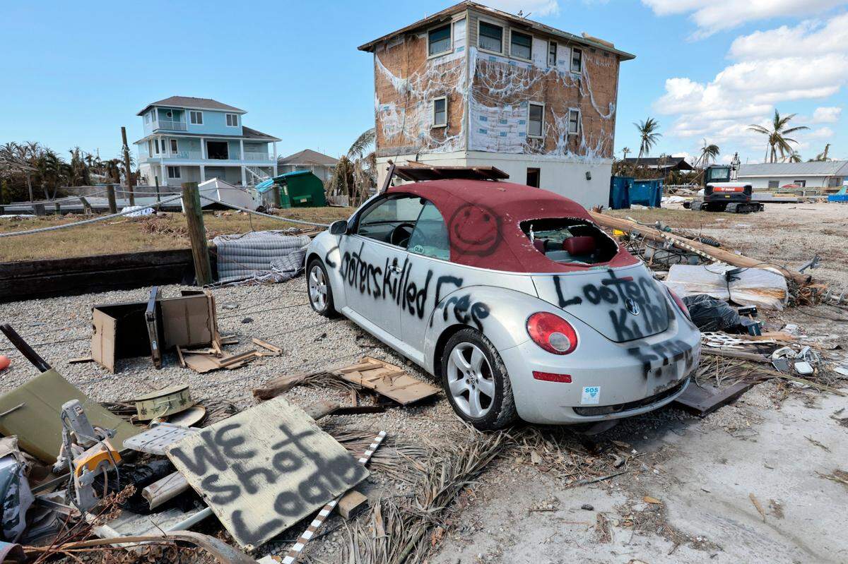 Makeshift signs are displayed in front of a damaged home caused by Hurricane Ian in St. James City, an unincorporated community, on Pine Island on Tuesday, Oct. 4, 2022.