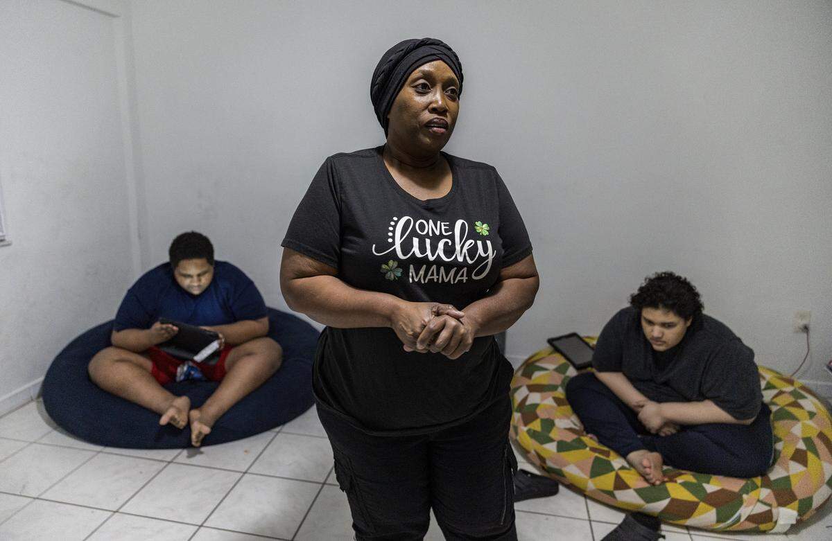 Single mom Fabiola Bodkin talks about her family issues flanked by her sons Ethan (left) and Liam, at their apartment provided by the Homeless Trust after the family had been living in a motel and a homeless shelter following their eviction from an apartment. on Tuesday, December 16, 2025.