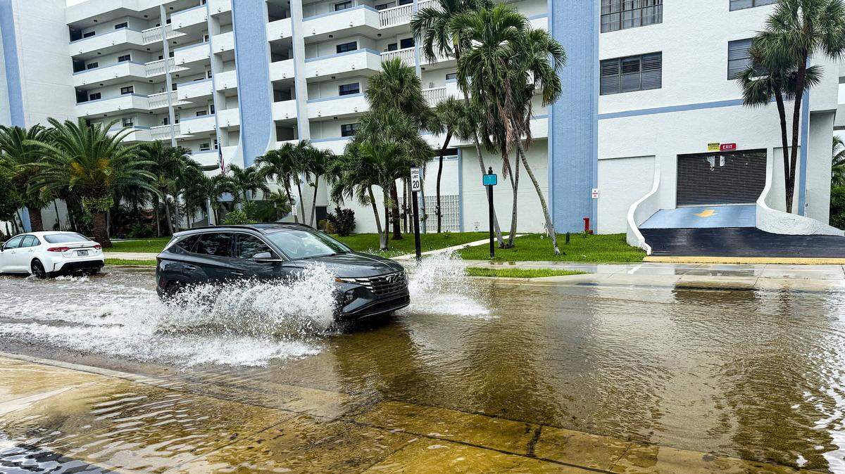 A car drives through floodwaters on North Bay Road in Sunny Isles Beach, Florida, after heavy rain on Saturday, Aug. 9, 2025.