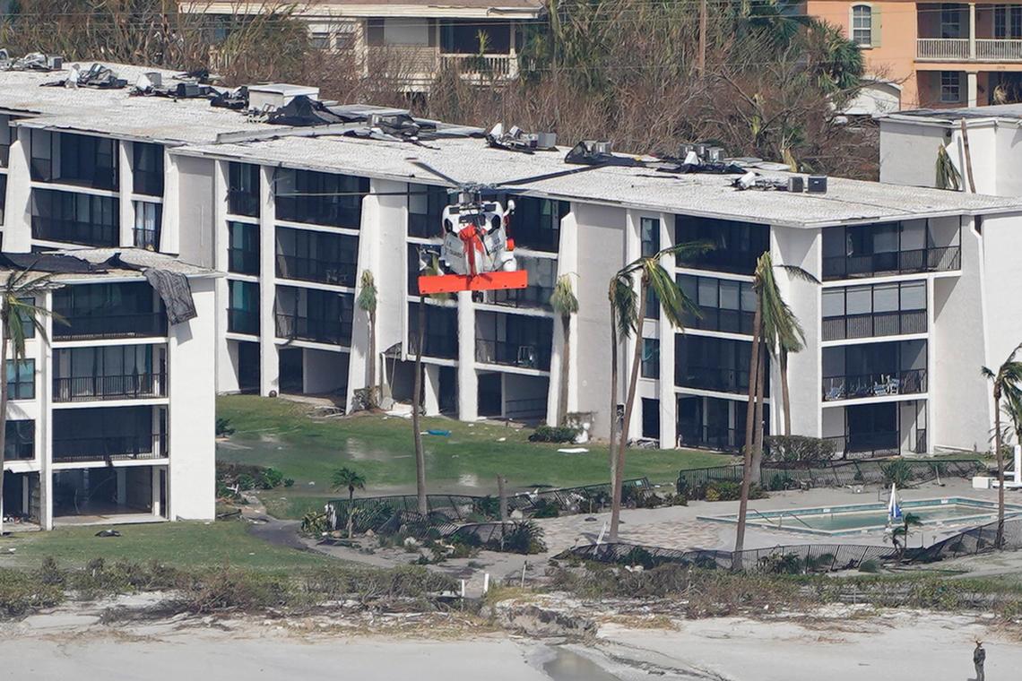 A Coast Guard helicopter flies over damaged homes and buildings in the aftermath of Hurricane Ian, Thursday, Sept. 29, 2022, on Sanibel Island, Fla. (AP Photo/Wilfredo Lee)