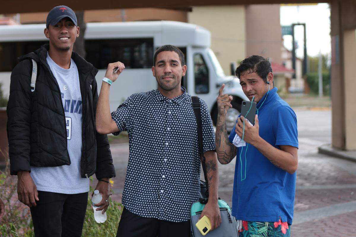 Pedro Escalona, far right, talks on the phone as he boards a charter bus with 20 other migrants after his planned flight from San Antonio to Delaware was canceled on Sept. 20.