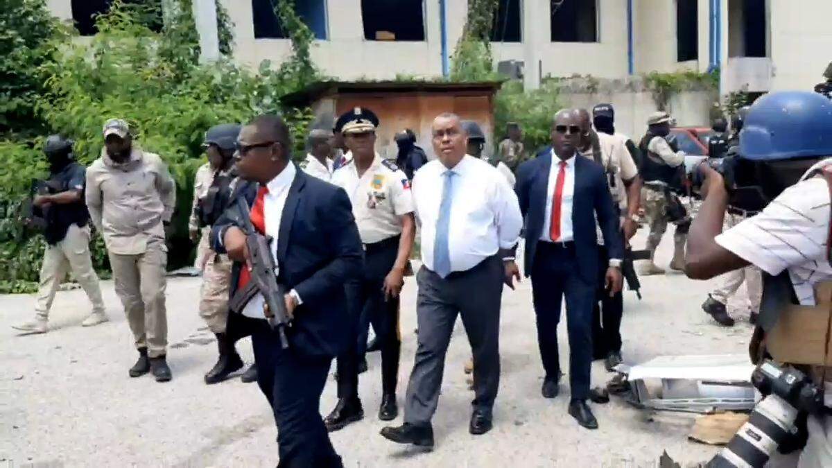 Haiti Prime Minister Garry Conille (center, white shirt) toured the site of the country’s largest public hospital on Tuesday, July 9, 2024, alongside Haiti National Police Chief Rameau Normil, left. The visit occurred a day after Normil announced police had taken back control of the site of the Hospital of the State University of Haiti, also known as the General Hospital, from armed gangs after months of attacks in the area. Normil made the announcement during the first joint press conference he held with the head of the Kenya-led Multinational Security Support mission, Godfrey Otunge.
