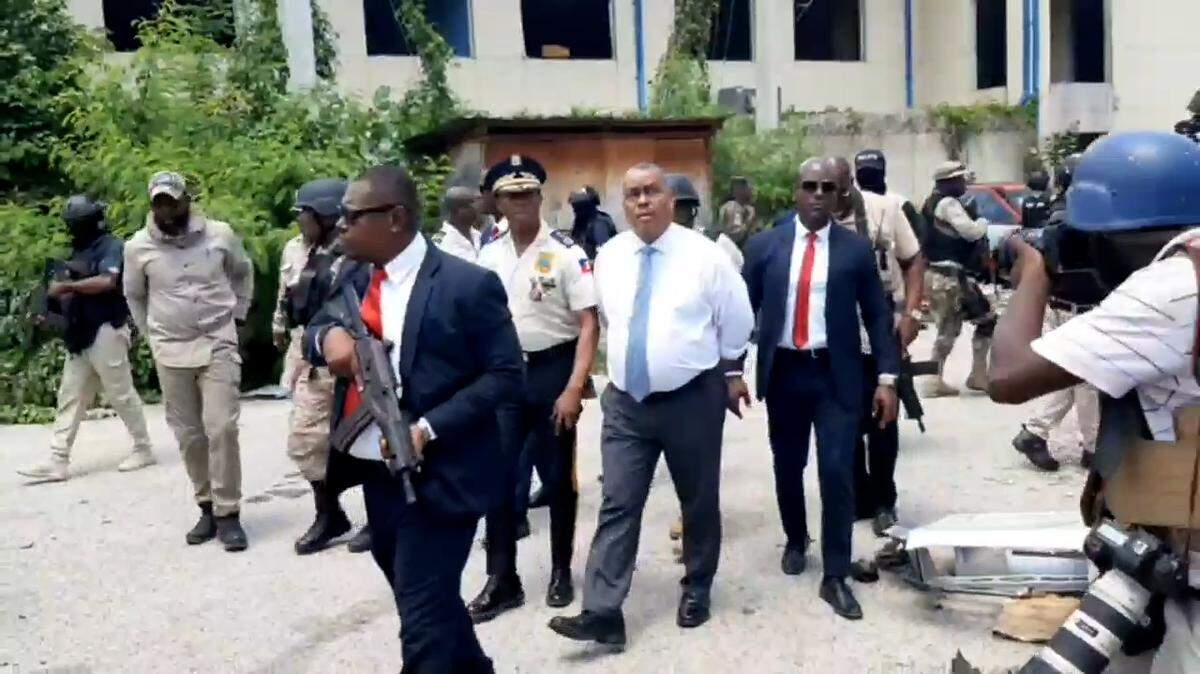 Haiti Prime Minister Garry Conille (center, white shirt) toured the site of the country’s largest public hospital on Tuesday, July 9, 2024 alongside Haiti National Police Chief Rameau Normil, left. The visit occurred a day after Normil announced police had taken back control of the site of the Hospital of the State University of Haiti, also known as the General Hospital, from armed gangs after months of attacks in the area.