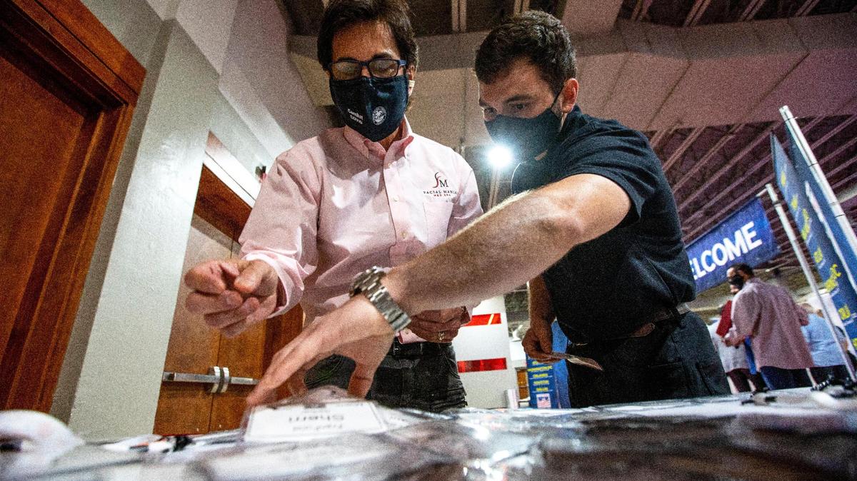 Two exhibitors for ‘Facial Mania’ find their name tags during the opening of the Franchise Expo, at Miami Airport & Convention Center (MACC) in Miami, Florida, on Friday, Mar., 12, 2021. The Franchise Expo is the first trade show being held in Miami since the COVID-19 pandemic began.