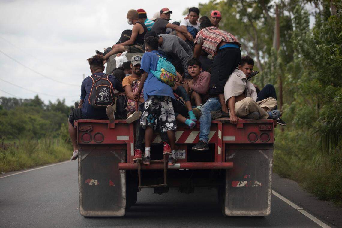 Migrants ride on the back of a freight truck that slowed down to let them jump on in Rio Dulce, Guatemala, on Oct. 2, 2020. Mauro Verzzeletti, director of the Casa del Migrante in Guatemala City, said the storms Eta and Iota will increase poverty on top of the violence people already faced, forcing more to migrate.