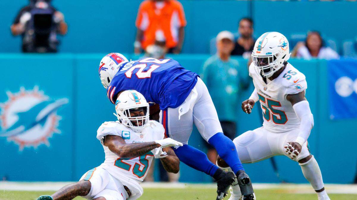 Miami Dolphins cornerback Xavien Howard (25) and Dolphins linebacker Jerome Baker (55) tackle Buffalo Bills running back Zack Moss (20) during the fourth quarter of an NFL football game at Hard Rock Stadium on Sunday, September 25, 2022 in Miami Gardens, Florida.