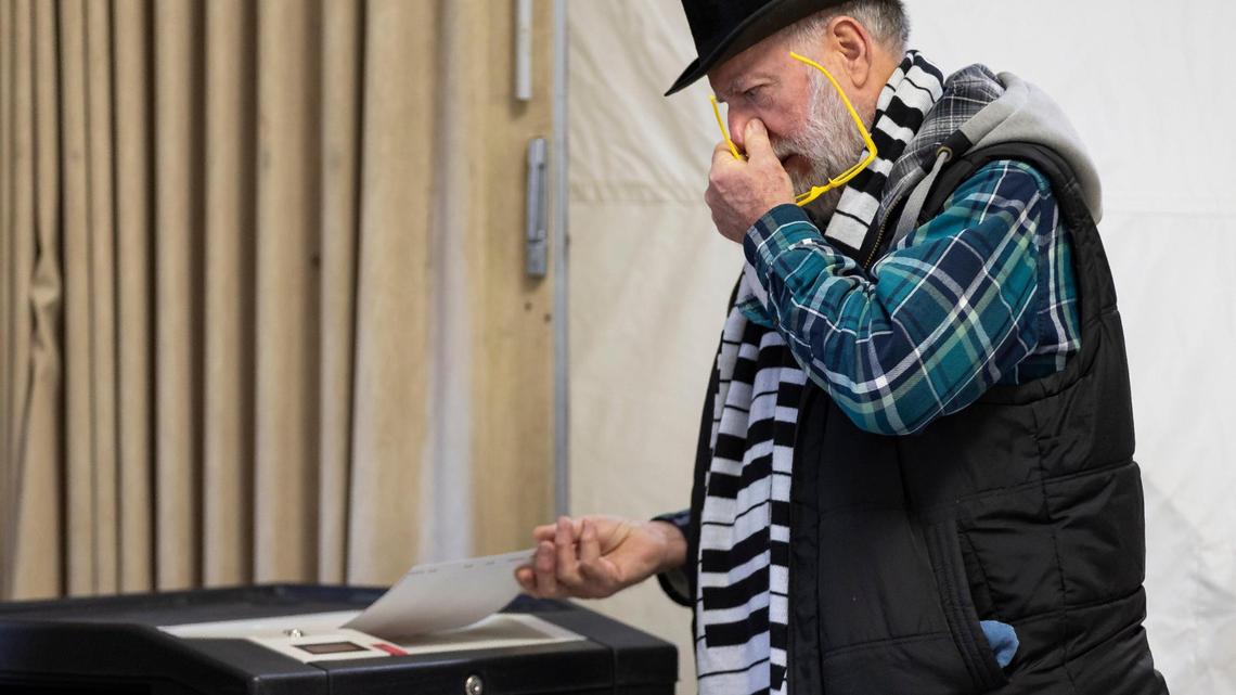 Brian Pfitzer, 70, holds his nose while entering his ballot in the New Hampshire Presidential primaries at a polling site inside Christ the King Parish Hall on Tuesday, Jan. 23, 2024, in Concord, New Hampshire.
