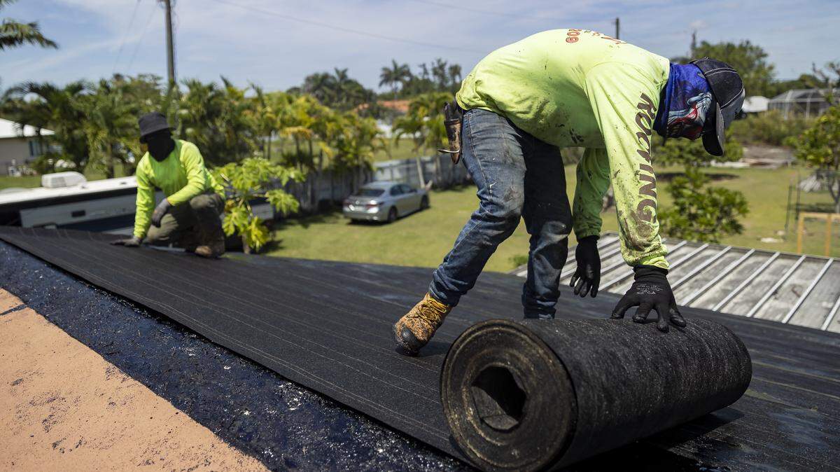 Jorge Tzunux, right, and Danilo Mateo work on a Homestead home’s roof in 2023