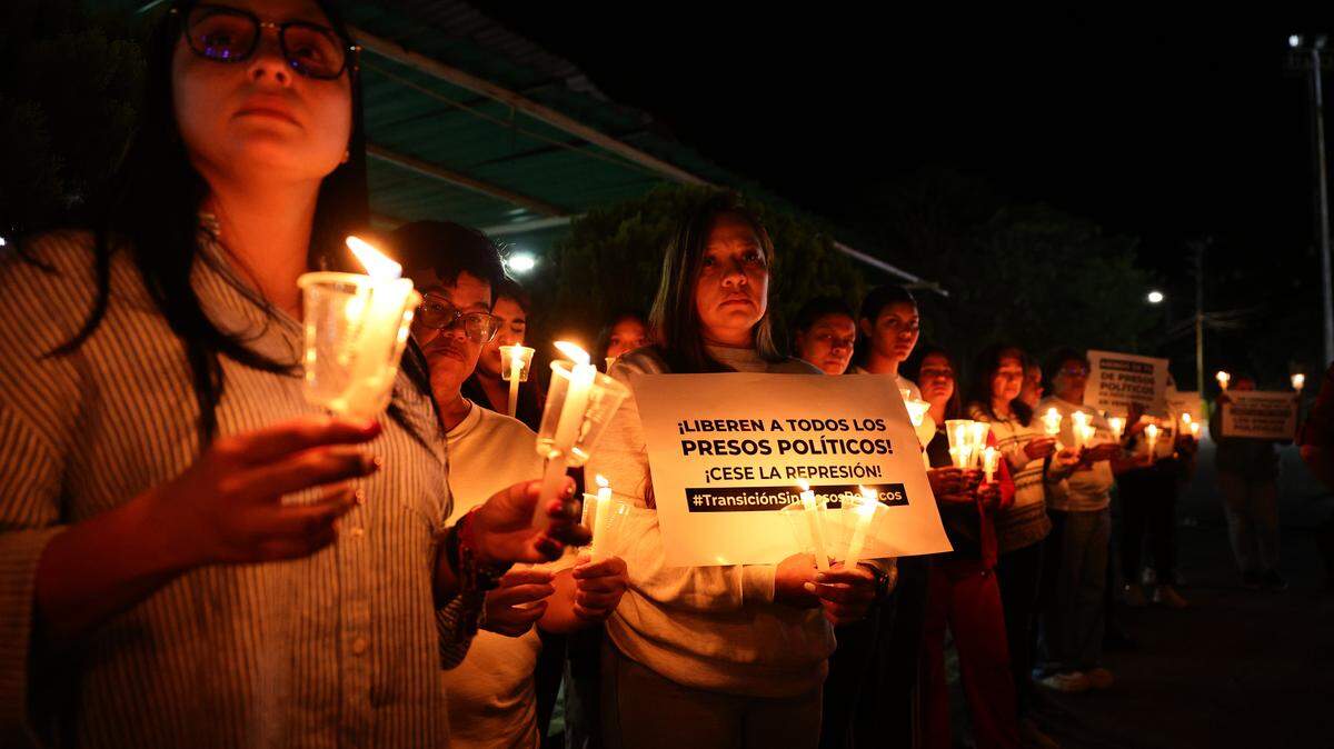 A relative of political prisoners holds candles and a sign that reads in Spanish "¡Liberen a todos los presos politicos! ¡Cese la represión!" (Free all political prisoners. Stop the repression) during a vigil while waiting updates on the release of prisoners outside "El Rodeo" prison on January 09, 2026 in Miranda, Venezuela. 