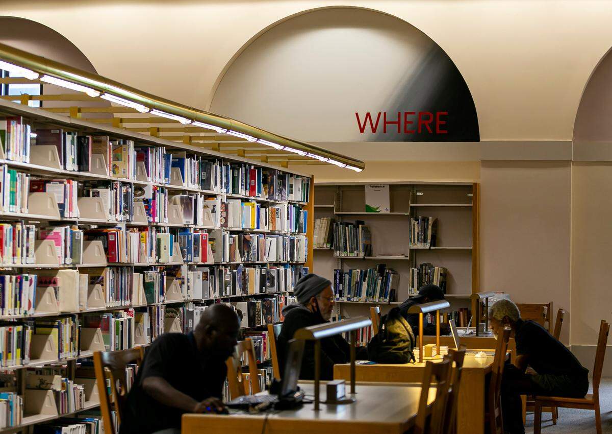 Patrons at the Miami-Dade County Main Library at downtown’s Cultural Center sit below a word mural by artist Edward Ruscha in a wall arch.