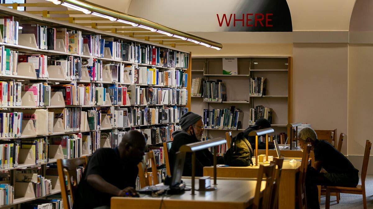 Patrons at the Miami-Dade County Main Library at downtown’s Cultural Center sit below a word mural in a wall arch by artist Edward Ruscha.