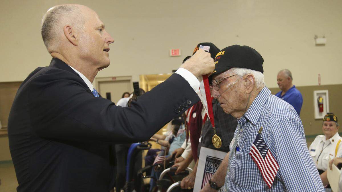 Florida Gov. Rick Scott gives the Governor’s Veterans Service Award to U.S. Army World War II veteran “Jeep” Rafeld during a ceremony at the Florida National Guard Armory in Ocala, Wednesday, Aug. 29, 2018.