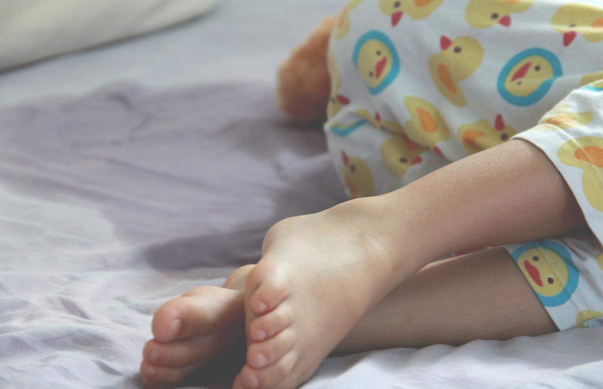 young child wets bed in pajamas
