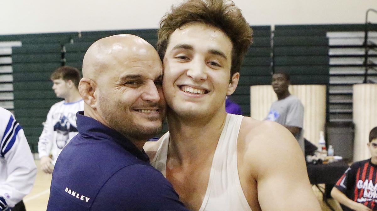 South Dade HS wrestling head coach Vic Balmeceda hugs his son Brevin after his victory in 160-pound class Region 4-3A wrestling finals on Saturday at Ronald Reagan High.