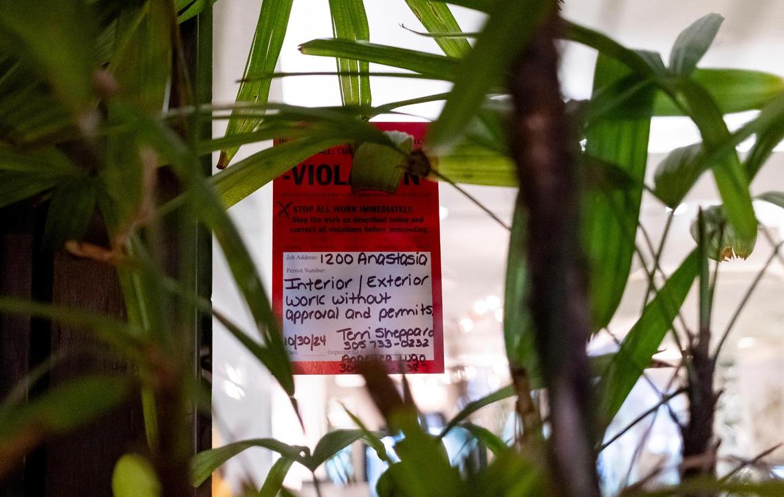 A violation notice for unpermitted renovation work, obscured by a plant placed in front of it, was posted by Coral Gables officials at the ground-floor entrance to the historic Biltmore Hotel. The city stopped work that covered up historic architectural features at the publicly owned hotel.