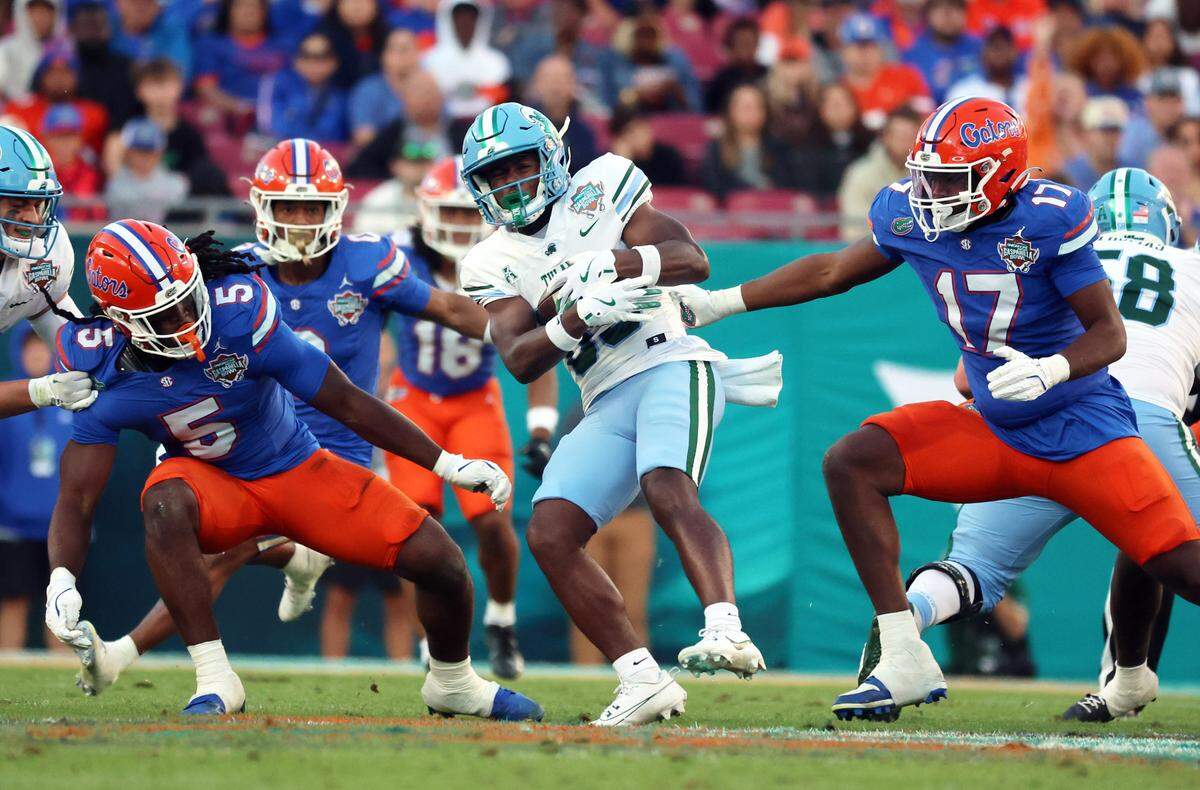 Dec 20, 2024; Tampa, FL, USA; Florida Gators linebacker Myles Graham (5) and Florida Gators edge LJ McCray (17) tackle Tulane Green Wave wide receiver Bryce Bohanon (83) during the second quarter at Raymond James Stadium. Mandatory Credit: Kim Klement Neitzel-Imagn Images