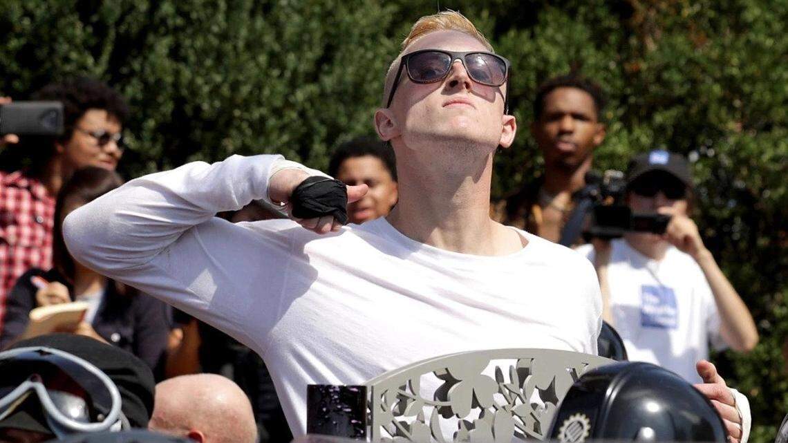 At 2017 Unite the Right rally in Charlottesville, Virginia, a man makes a slashing motion across his throat toward counter-protesters as he marches.
