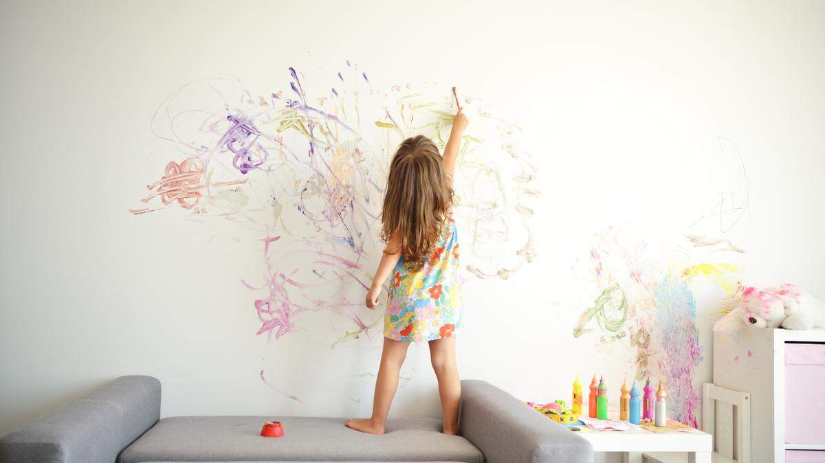 young girl drawing on wall