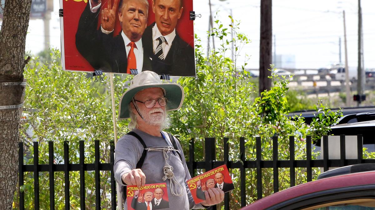 Robert Welsh, a South Miami city commissioner, displays an anti-President Donald Trump banner on NE Second Ave., before the Democratic presidential debates at the Adrienne Arsht Center for the Performing Arts in Miami on June 26, 2019.