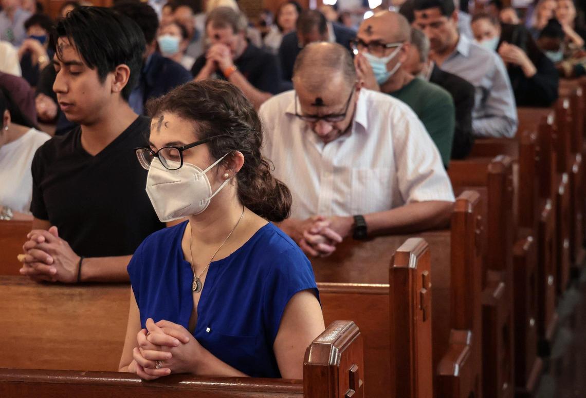 Catholic worshipers bow their heads in prayer after receiving communion during Ash Wednesday Mass. Archbishop Thomas Gerard Wenski held Ash Wednesday Mass at Gesu Church for Miami’s Catholic community as part of the start of the season of Lent on Wednesday, March 3, 2022.